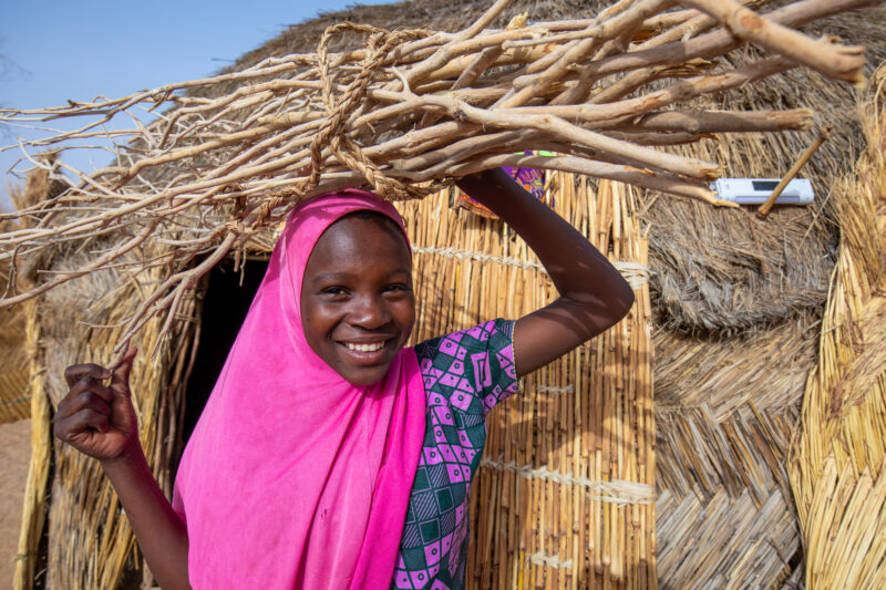 Collecting Firewood — Girl with the firewood that she has collected to cook the meal. — Africa, Child, Colorful, Education, Eyes Open