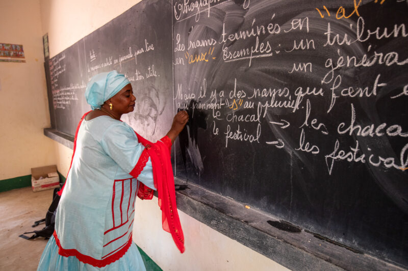 Teacher at Blackboard — Teacher writes out lesson on a blackboard at a school in Niger, Africa. — Africa, Education, Niger, One Face, Person