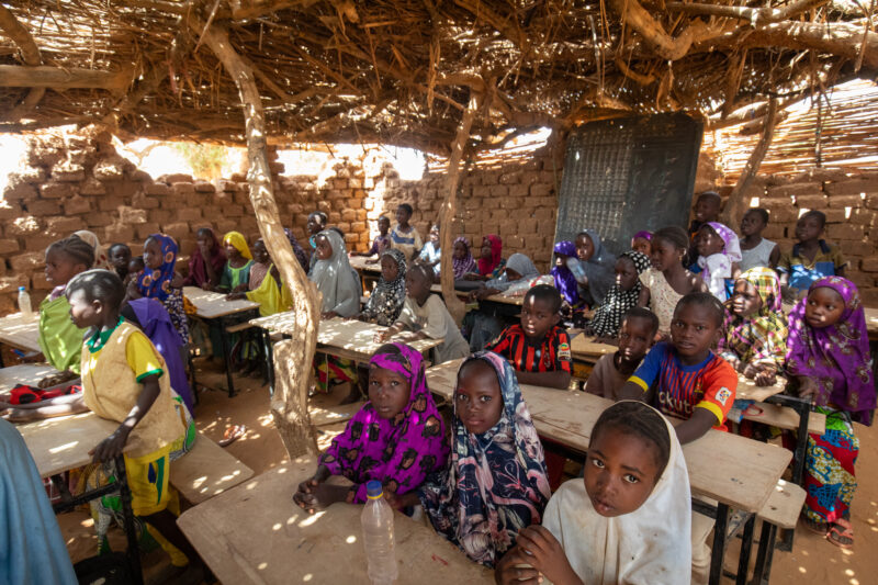 Temporary Classroom — Students in Niger, Africa, attend school in a classroom made of mud and sticks. — Adult, Africa, Child, Education, Eyes Closed