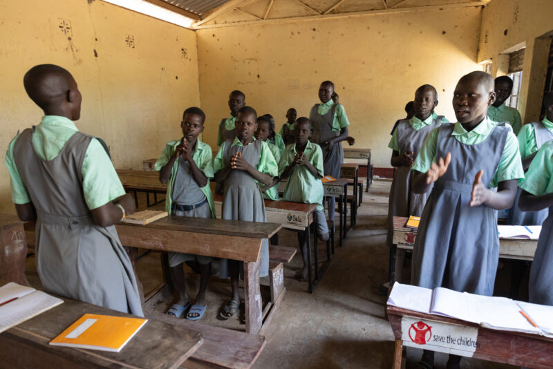 Singing in School — Girls happy to be in school, sing, "we are happy, we are happy" (See video Clip) — Adult, Beard, Eyes Closed, Eyes Open, Frontal Face