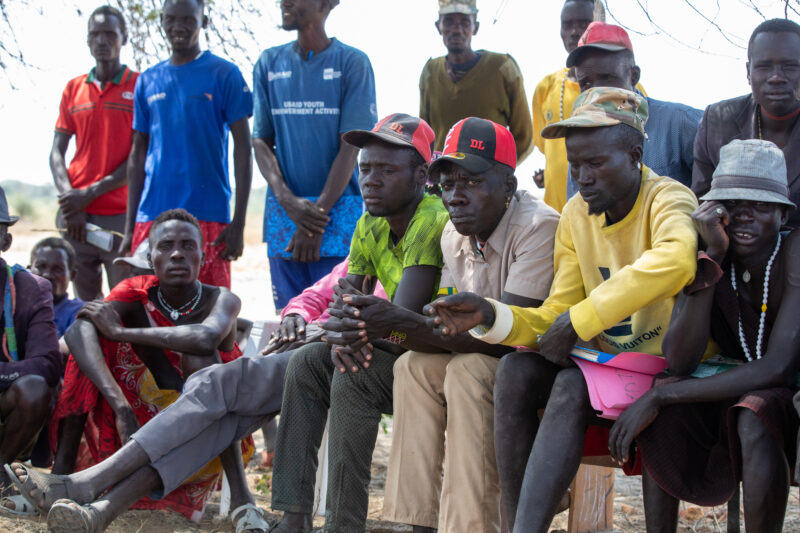 Adult Education — Adults under a tree gather for education on health, food security and income generation. — Adult, Beard, Boat, Eyes Closed, Eyes Open