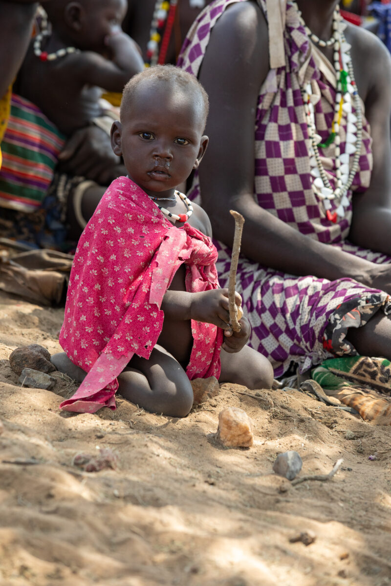Adult Education — Adults under a tree gather for education on health, food security and income generation. — Child, Eyes Open, Frontal Face, Male, One Face