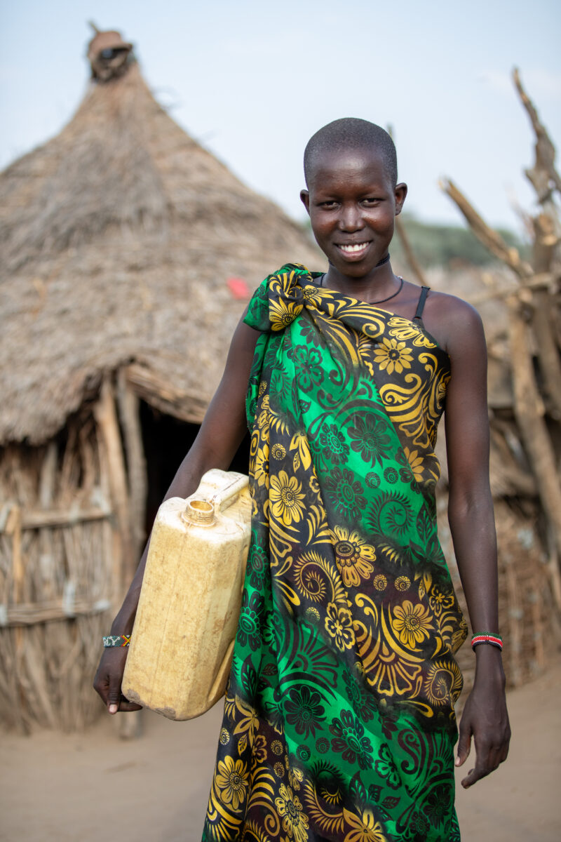 Girl with Water Container — Young girl in South Sudan Africa poses with her jerry can, before heading out to collect water. — Adult, Eyes Open, Frontal Face,...