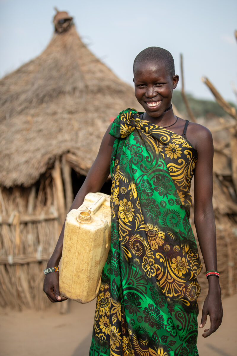 Girl with Water Container — Young girl in South Sudan Africa poses with her jerry can, before heading out to collect water. — Adult, Eyes Open, Female, Front...