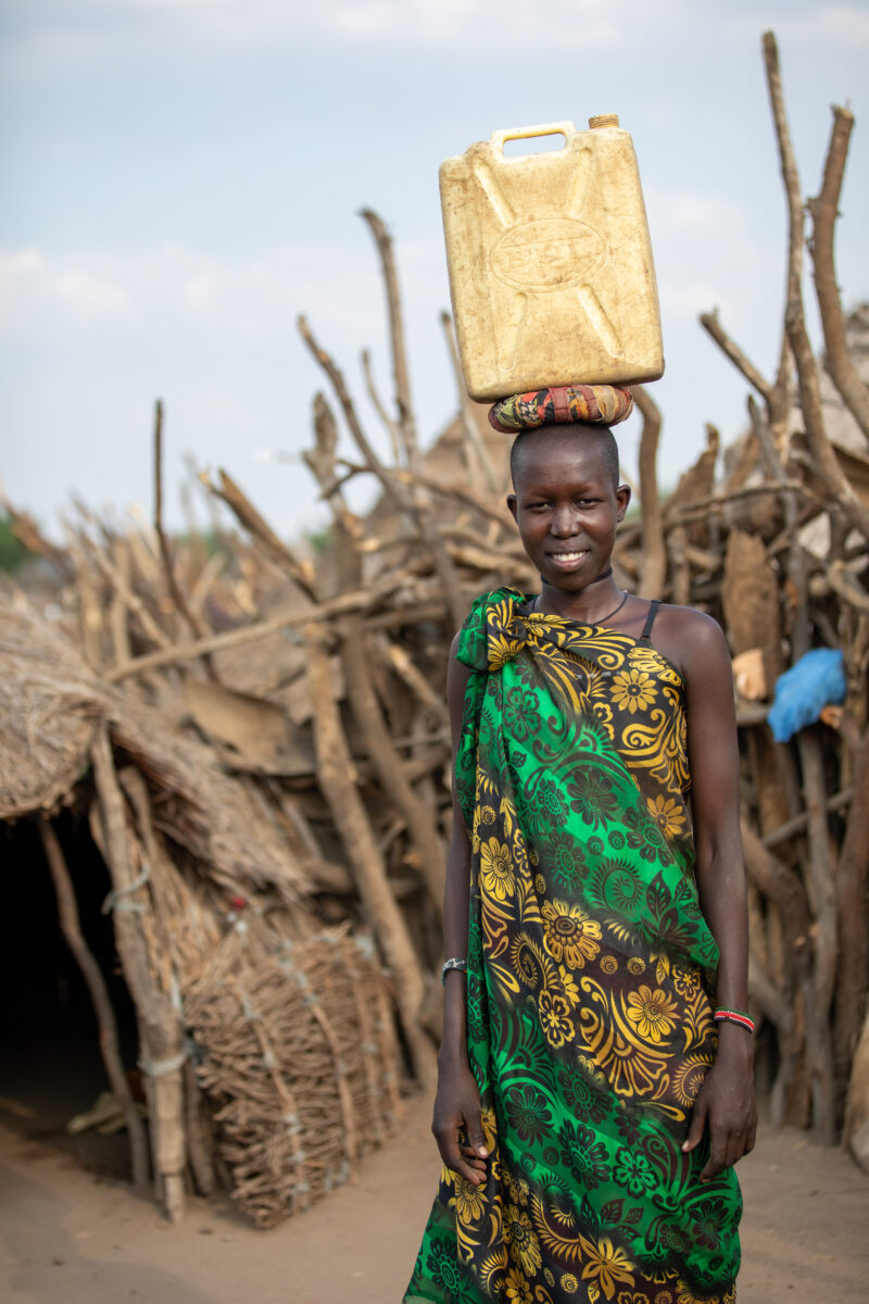 Girl with Water Container — Young girl in South Sudan Africa poses with her jerry can, before heading out to collect water. — Adult, Eyes Open, Frontal Face,...