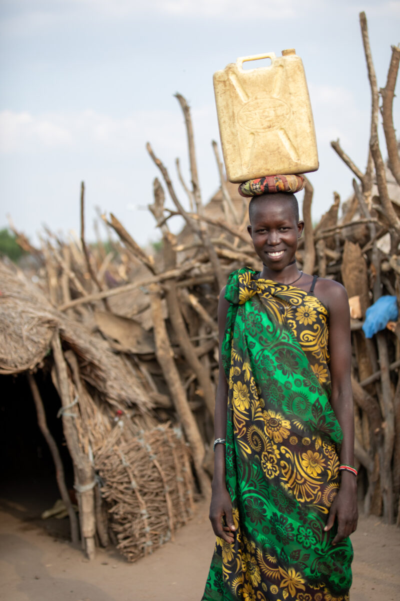 Girl with Water Container — Young girl in South Sudan Africa poses with her jerry can, before heading out to collect water. — Adult, Eyes Open, Female, Front...