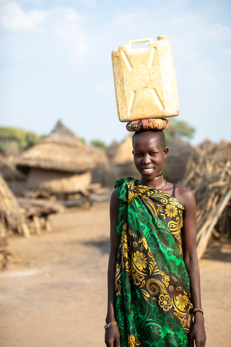 Girl with Water Container — Young girl in South Sudan Africa poses with her jerry can, before heading out to collect water. — Eyes Open, Frontal Face, Male, ...