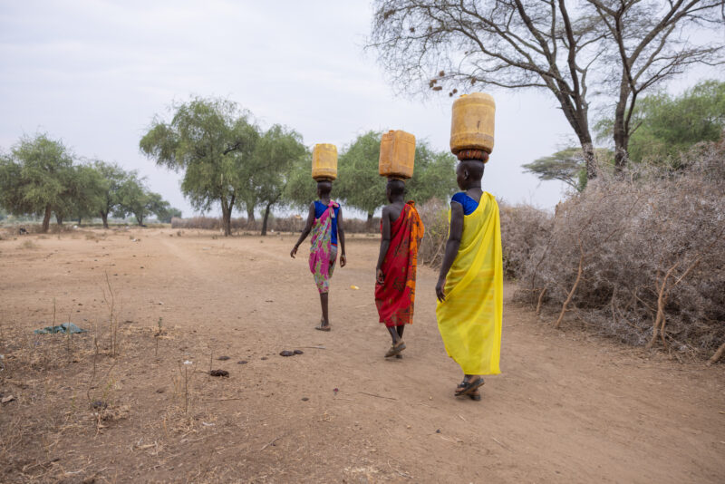 Collecting Water in Africa — Once or twice each day, young girls go to the water source near their village to collect water for their family. — Person, South...