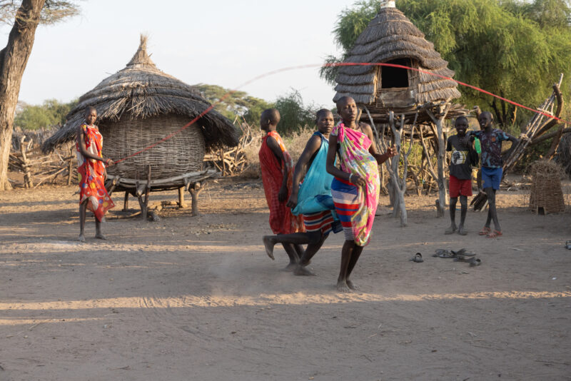 Skipping in Africa — Young girls in South Sudan Africa enjoy skipping in the evening light — Adult, Eyes Open, Frontal Face, Group, Male