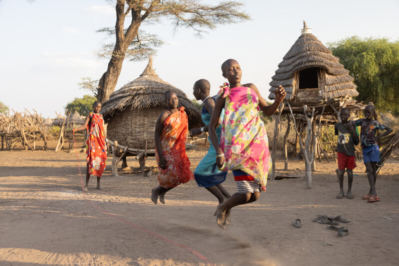 Skipping in Africa — Young girls in South Sudan Africa enjoy skipping in the evening light — Adult, Eyes Closed, Eyes Open, Female, Frontal Face