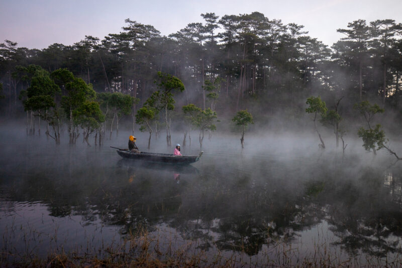 Early Morning on the Lake — Fog and mist rise up from a Lake in Vietnam making a scenic splender with a man in his fishing boat. — Boat, Colorless, Dark, Nat...