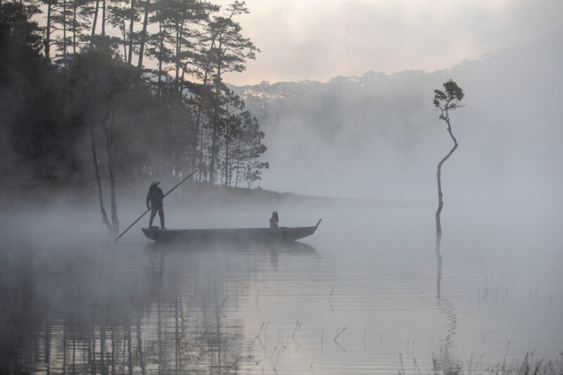 Early Morning on the Lake — Fog and mist rise up from a Lake in Vietnam making a scenic splender with a man in his fishing boat. — Fog, Nature, Person, Sport...