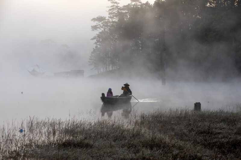 Early Morning on the Lake — Fog and mist rise up from a Lake in Vietnam making a scenic splender with a man in his fishing boat. — Boat, Canoe, Colorless, Fo...