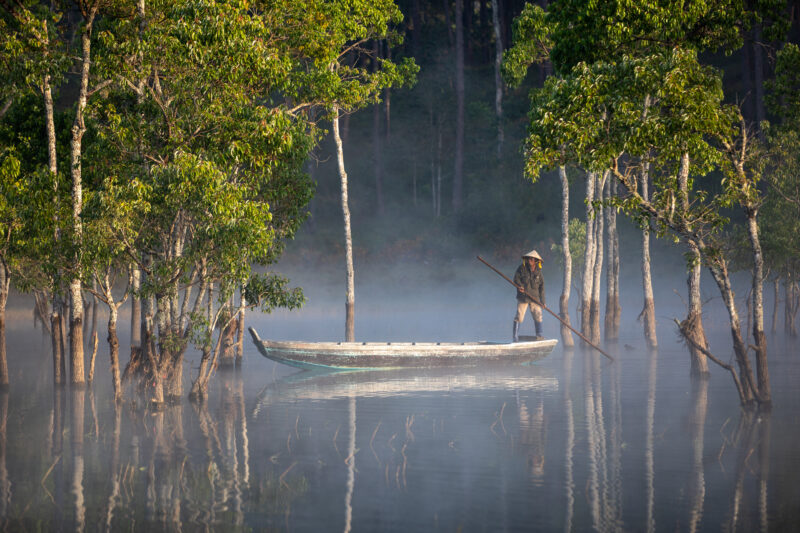Early Morning on the Lake — Fog and mist rise up from a Lake in Vietnam making a scenic splender with a man in his fishing boat. — Boat, Forest, Nature, Pers...