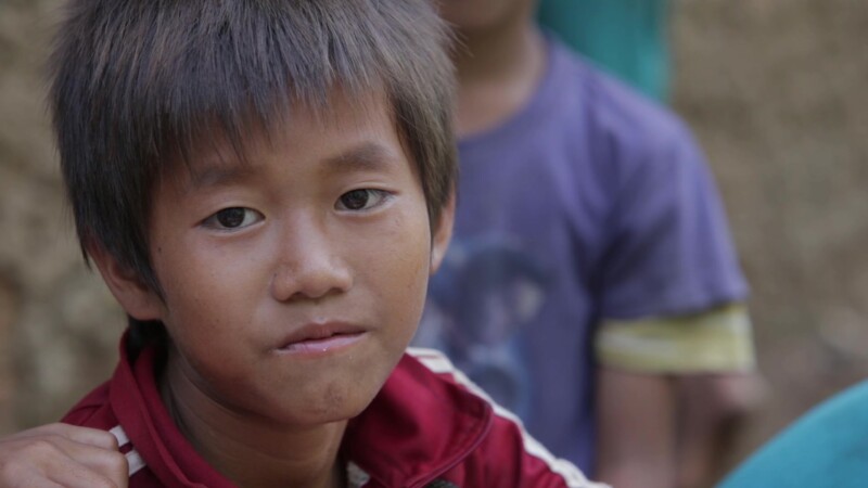 Happy for the Food — Stock Video Footage of Laos: Young boy gives a smile of thanks for the nutritious hot lunch provided for him and his friends, at a remot...