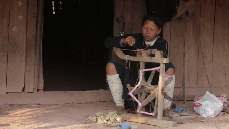Lanten Ethnic Woman by Doorway — Stock Video Footage of Laos: A woman of the Lanten ethnic group, sitting in the doorway of her home, works on her cotton spi...