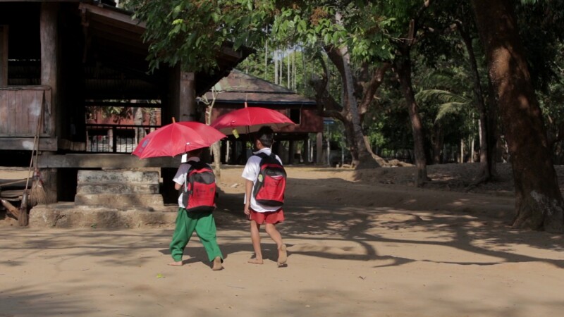 Walking to school — Students walking into their school in Myanmar, using umbrellas to protect them from the sun. — Burma, Karen, Karen State, Myanmar, jungle