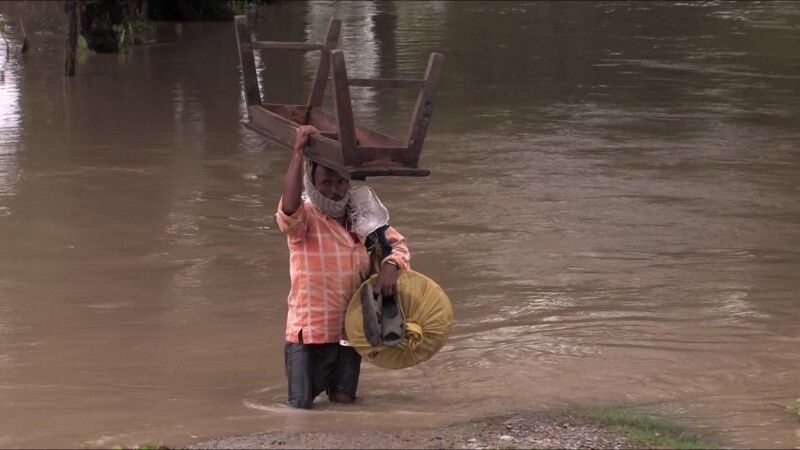Man in Nepal in Flood — Man in Nepal struggles to walk through flood waters with a few possessions — Nepal, IDP, Internally Displaced, man, flood