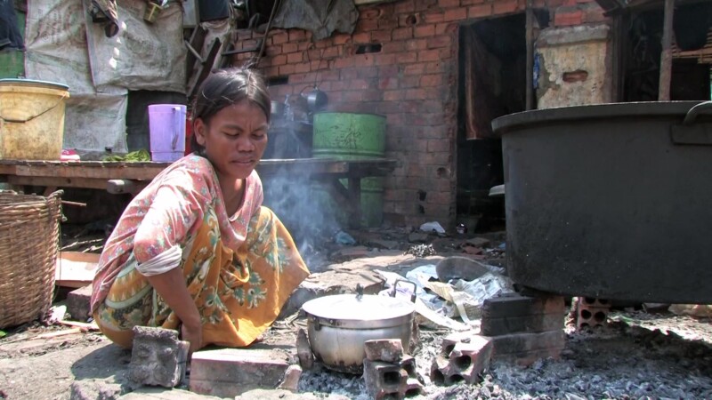 Woman in Poverty — A woman cooks over a fire behind her shanti town shelterKeywords: Poverty, Shantytown, slum, squatter Settlement, woman, cooking, food, fire