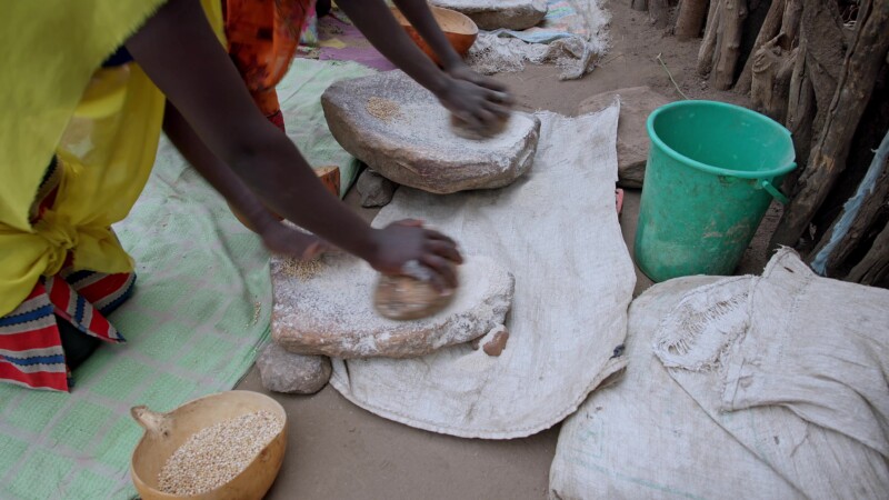 Grinding Flour — Girls in South Sudan grind grain into flour for cooking, using traditional grinding stones. — Africa, South Sudan, Rural, Remote, Pastoralists