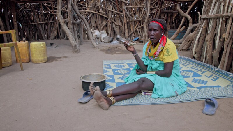 Mother Eats Alone — Woman in Africa takes her meal of sorghum alone on a matt inside the family compound. — Africa, South Sudan, Rural, Remote, Pastoralists