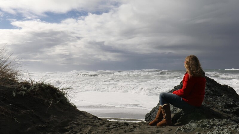 Watching the Waves — A woman sits near a beach on the Oregon coast, watching strong waves roll in. — United States, Scenic, Oregon, Coast, beach